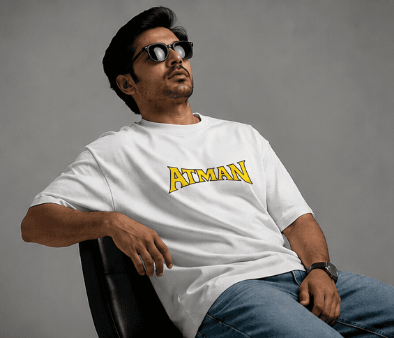White oversized t-shirt with yellow Atman text, black sunglasses
