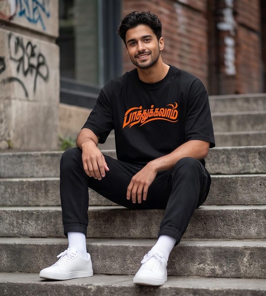 Man in black t-shirt with Tamil text, black pants, white sneakers