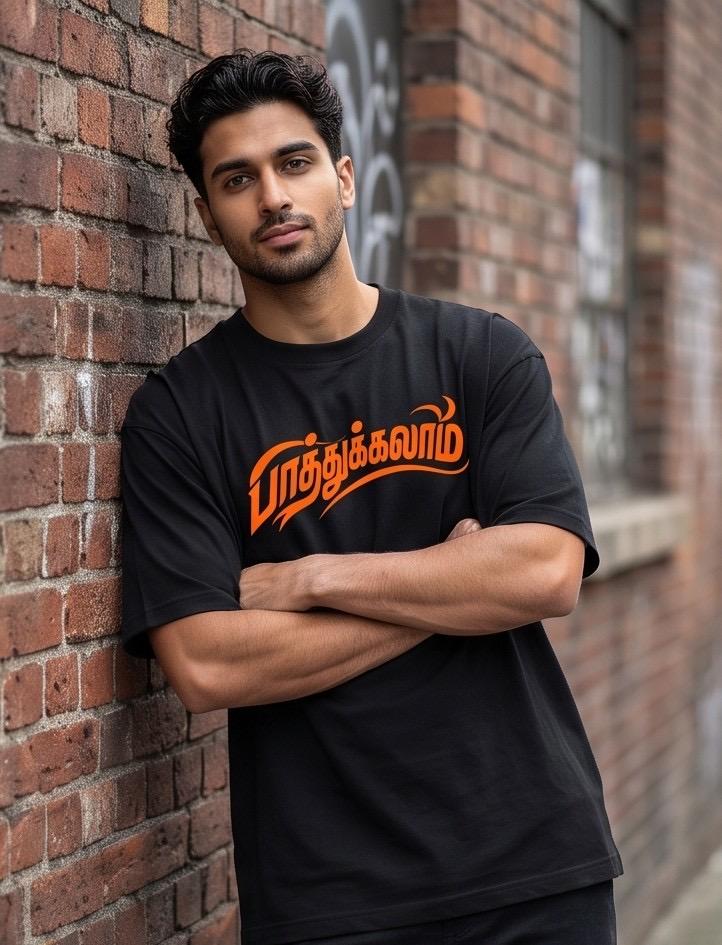 Black t-shirt with orange Tamil text, worn by man